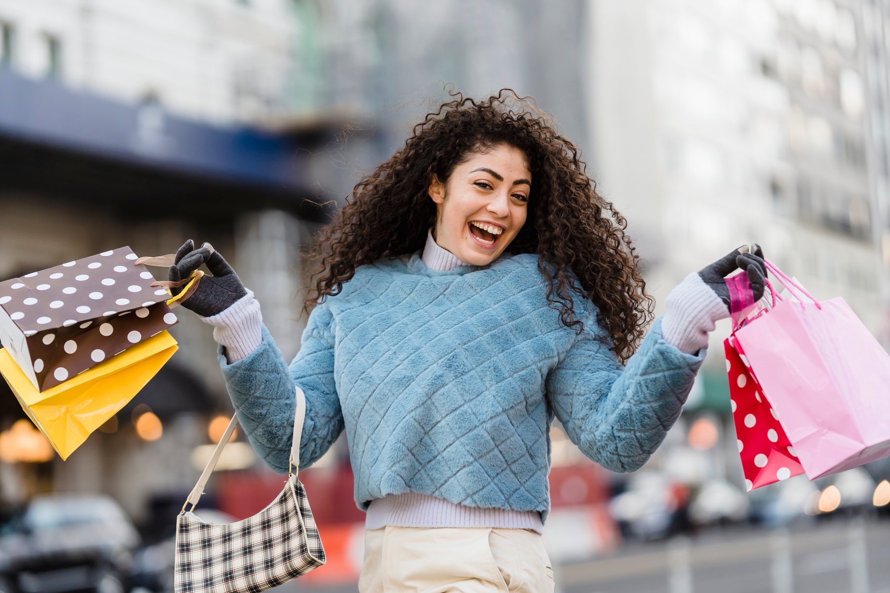 Happy ethnic woman demonstrating shopping bags